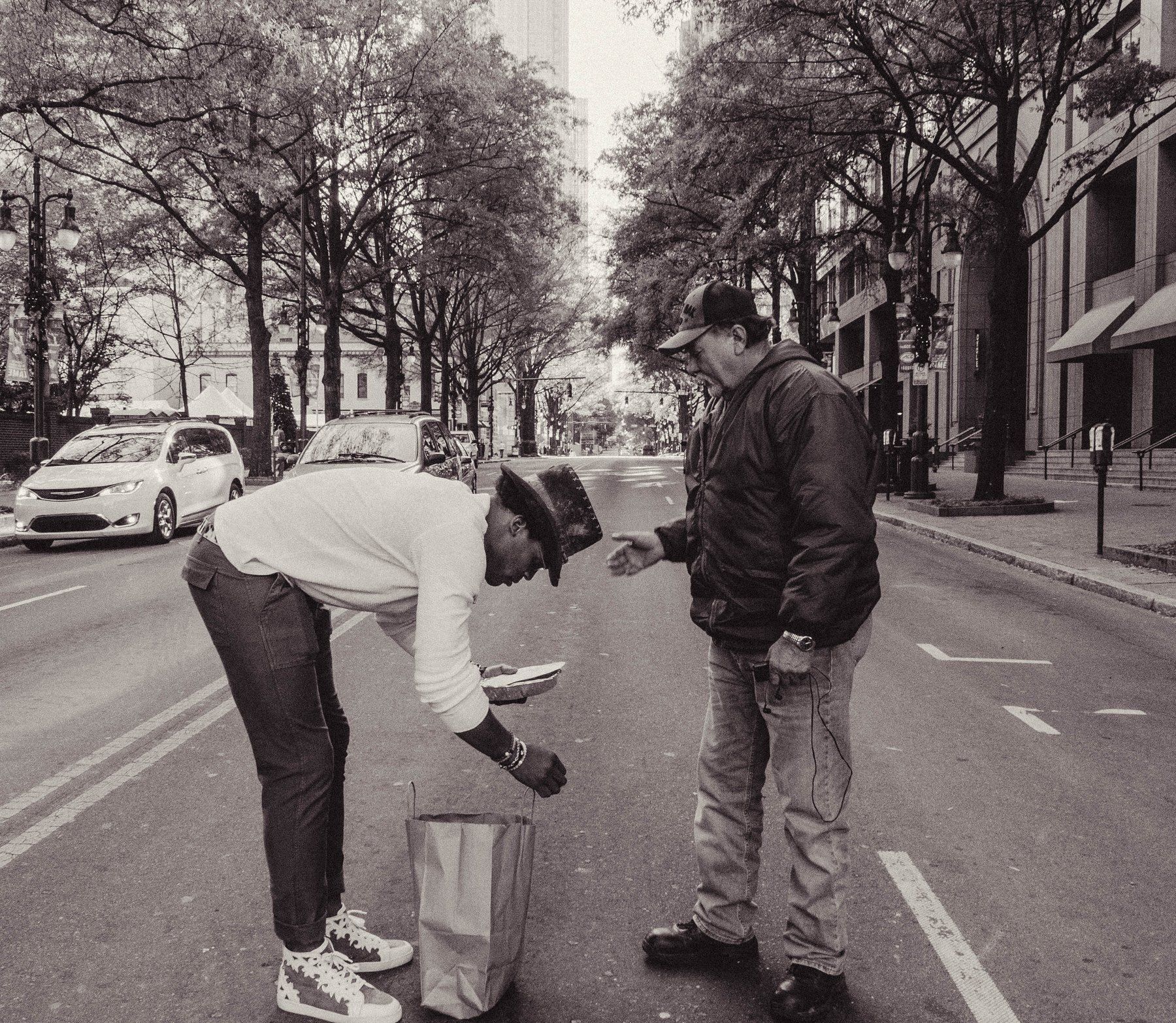 Cam Newton handing food to a man on Tryon Street, Charlotte, on Thanksgiving morning.